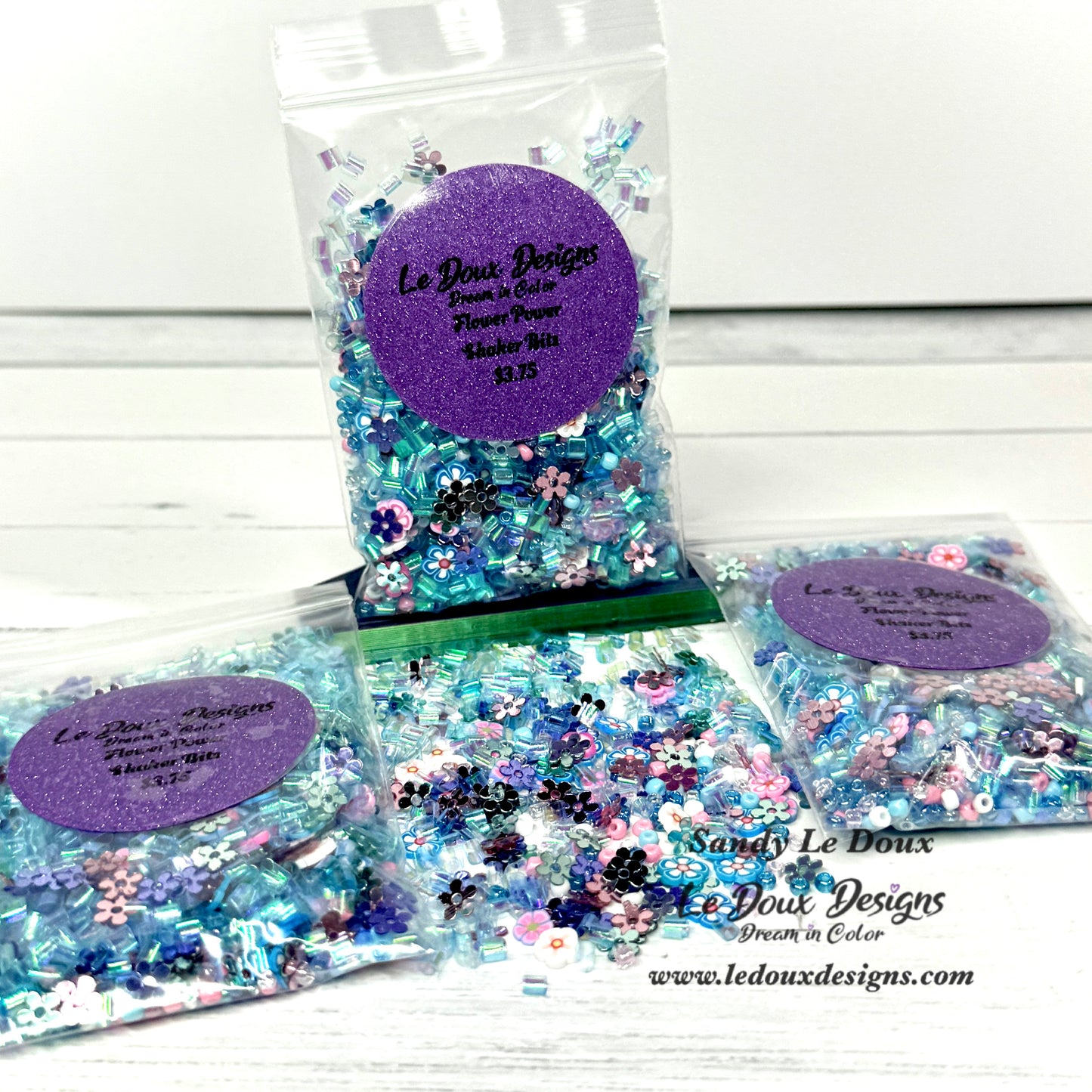 Packets of decorative confetti with a purple label on a white wooden surface