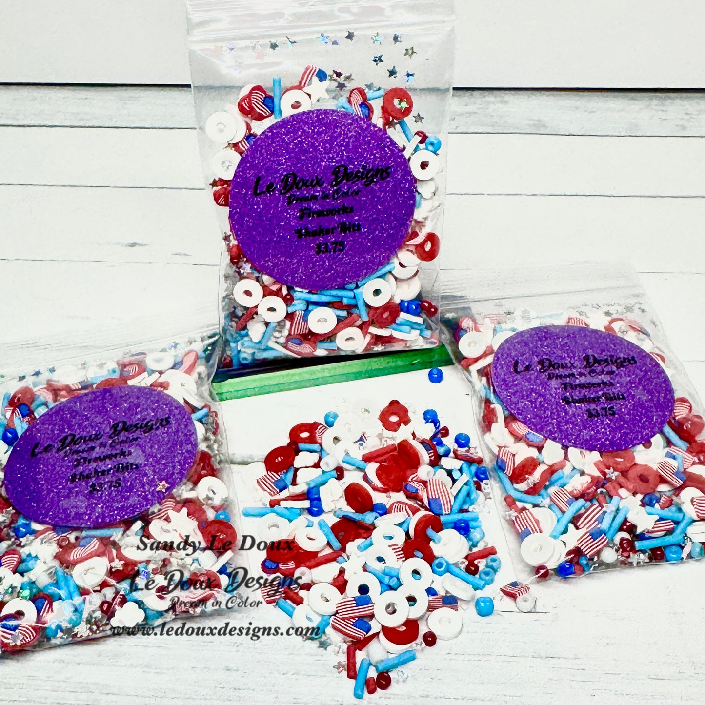 Three bags of patriotic-themed decorative items with 'Le Doux Design' branding on a wooden surface.