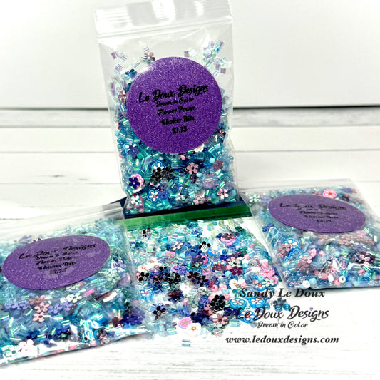 Packets of decorative confetti with a purple label on a white wooden surface