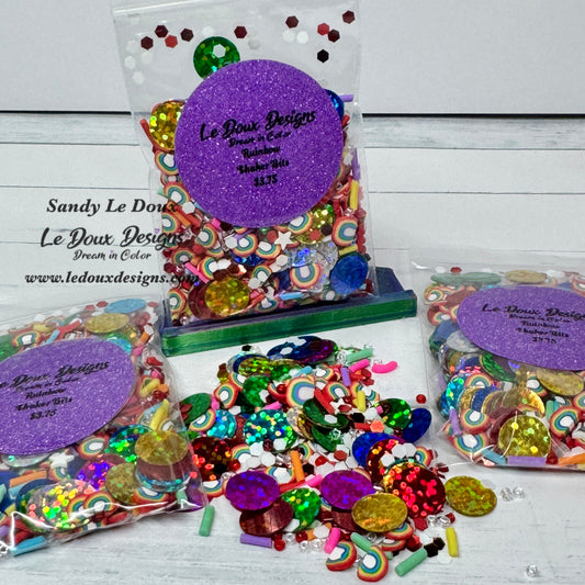 Colorful sequins and embellishments with Le Doux Designs packaging on a white wooden surface.